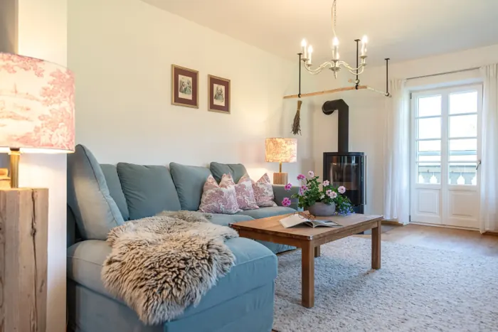 Wohnzimmer der Wohnung Lina mit blauem Sofa und Kaminofen